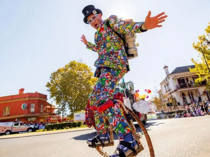 A performer in a patterned suit and top hat on spring stilts