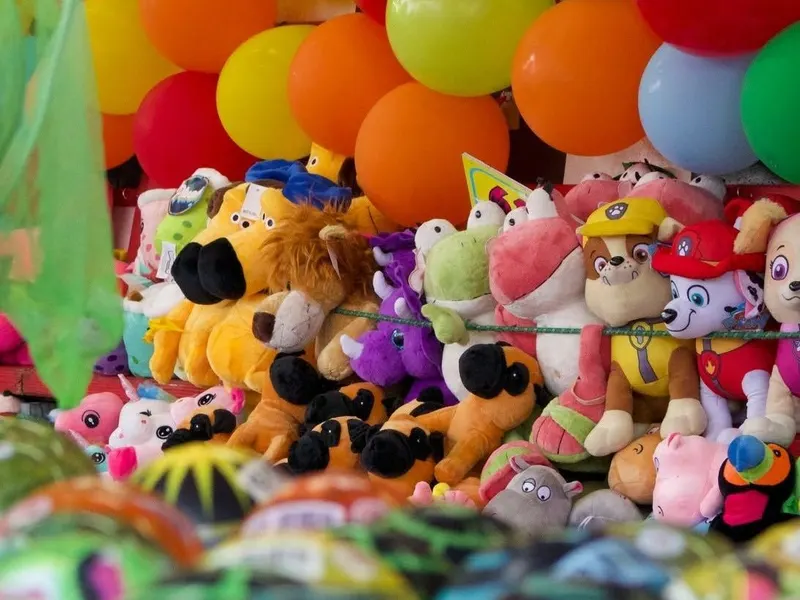 Plush toys and balloons piled up as prizes at a carnival game