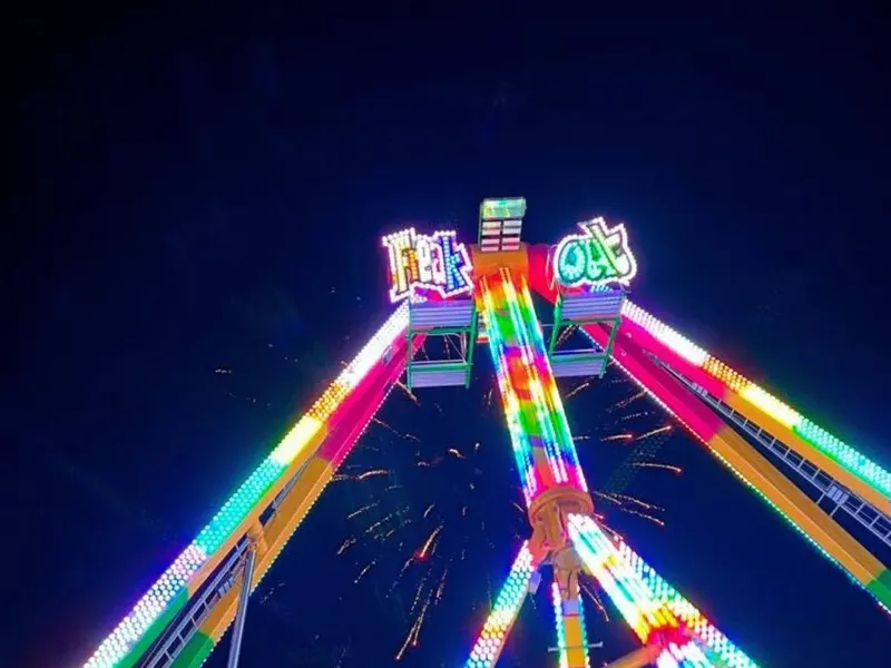 A pendulum ride lit up in rainbow lights against the night sky