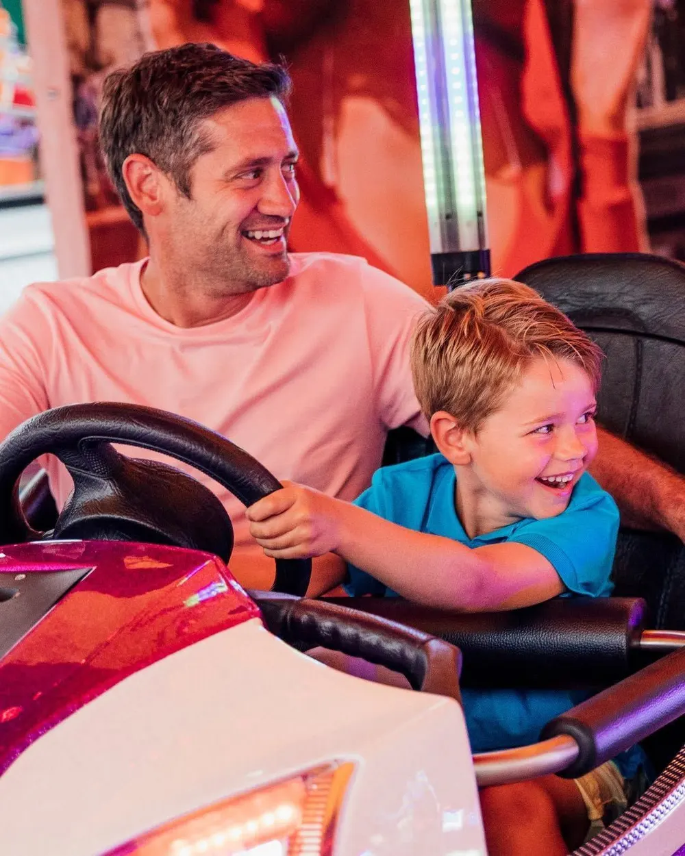 A dad and his son laughing together in a bumper car
